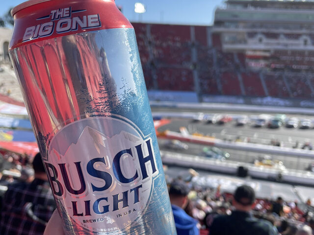 A fan holds up a Busch beer can with the race track at the Clash at the Coliseum in the background