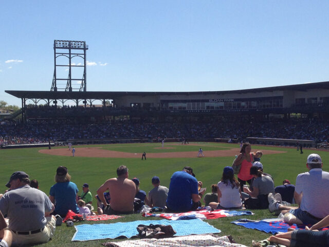Fans watch a spring training baseball game from a berm at Sloan Park in Mesa, Arizona