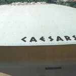 Overhead view of the Caesars Superdome in New Orleans, with signage visible on the white roof