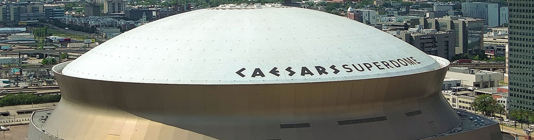 Overhead view of the Caesars Superdome in New Orleans, with signage visible on the white roof