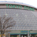 Exterior view of the Tokyo Dome stadium, with lighted green signage