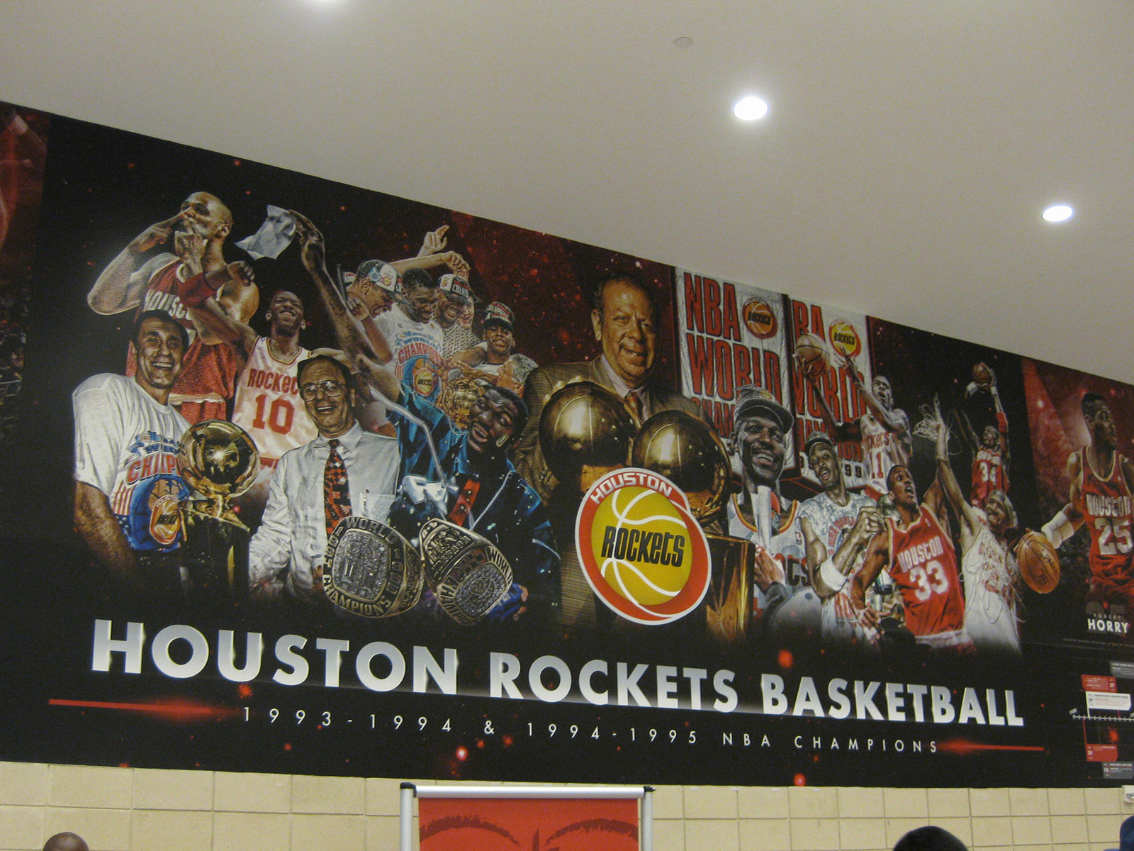 A mural depicting key figures in Rockets' 1990s-era NBA titles is displayed on the concourse at Toyota Center in Houston, Texas