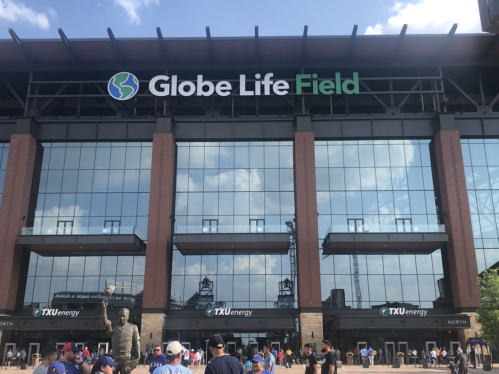 Fans gather next to a statue of Nolan Ryan in front of the entrance to Globe Life Field in Arlington, Texas