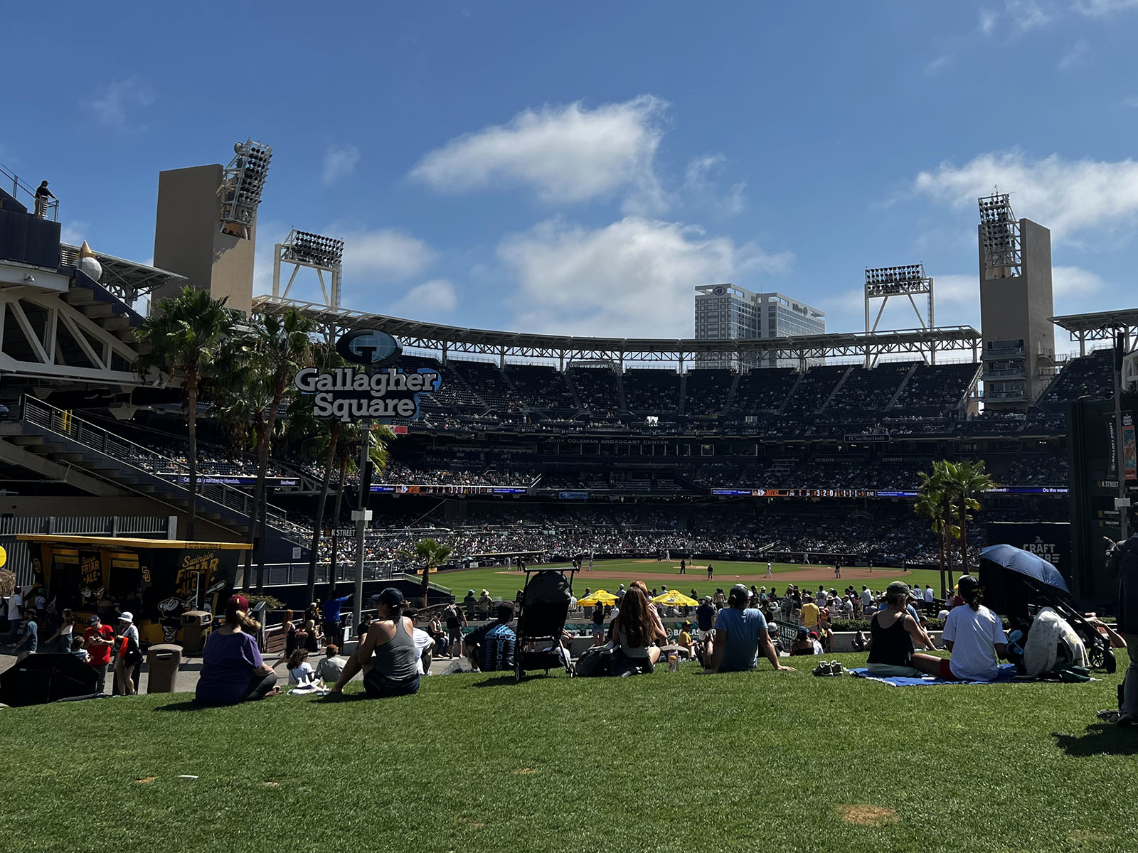 Fans sit on the lawn at Petco Park's Gallagher Square and watch a San Diego Padres game
