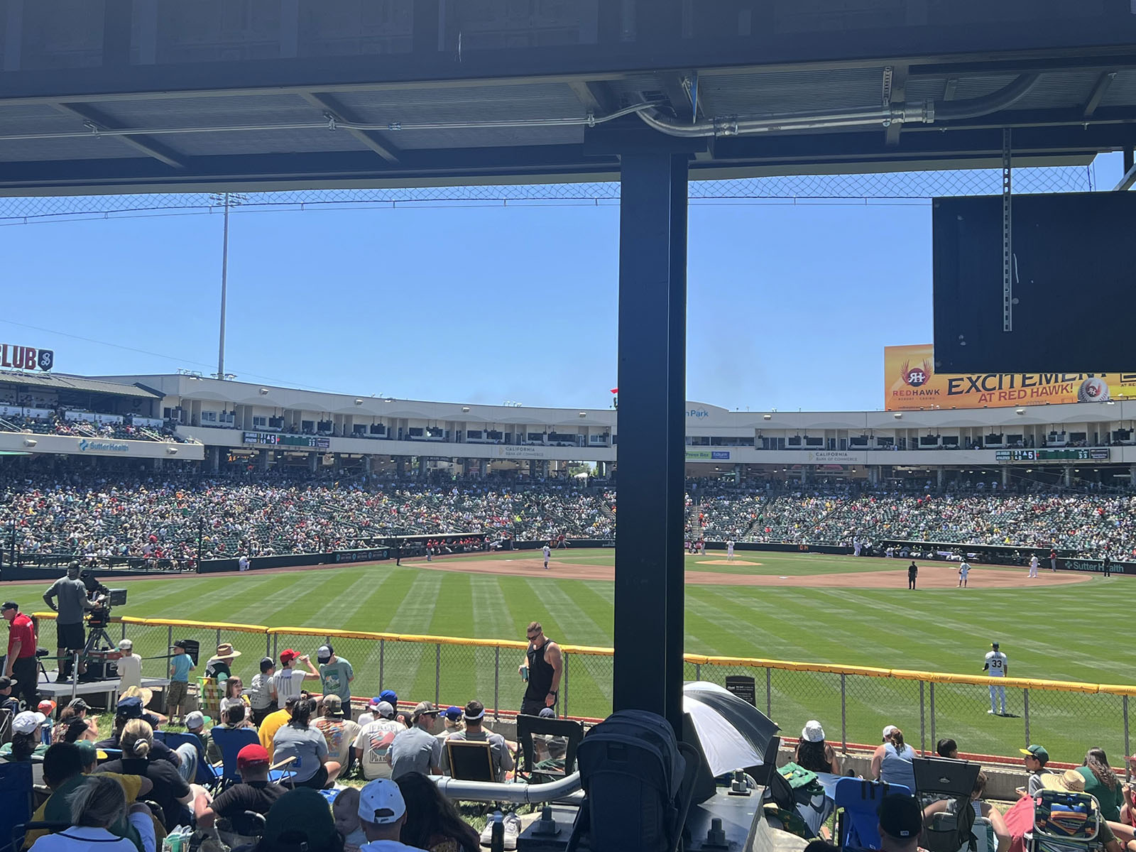 Fans watch an Athletics game from the grassy berm in right field at Sutter Health Park in West Sacramento, California