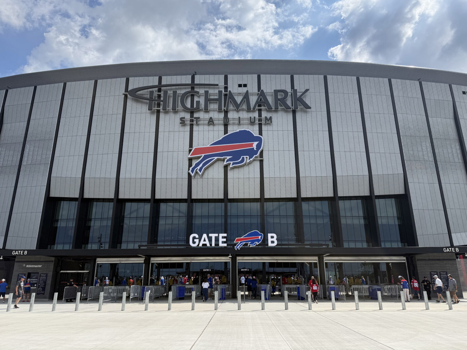 Signage and the Buffalo Bills logo hang above an entrance gate at Highmark Stadium in Orchard Park, New York
